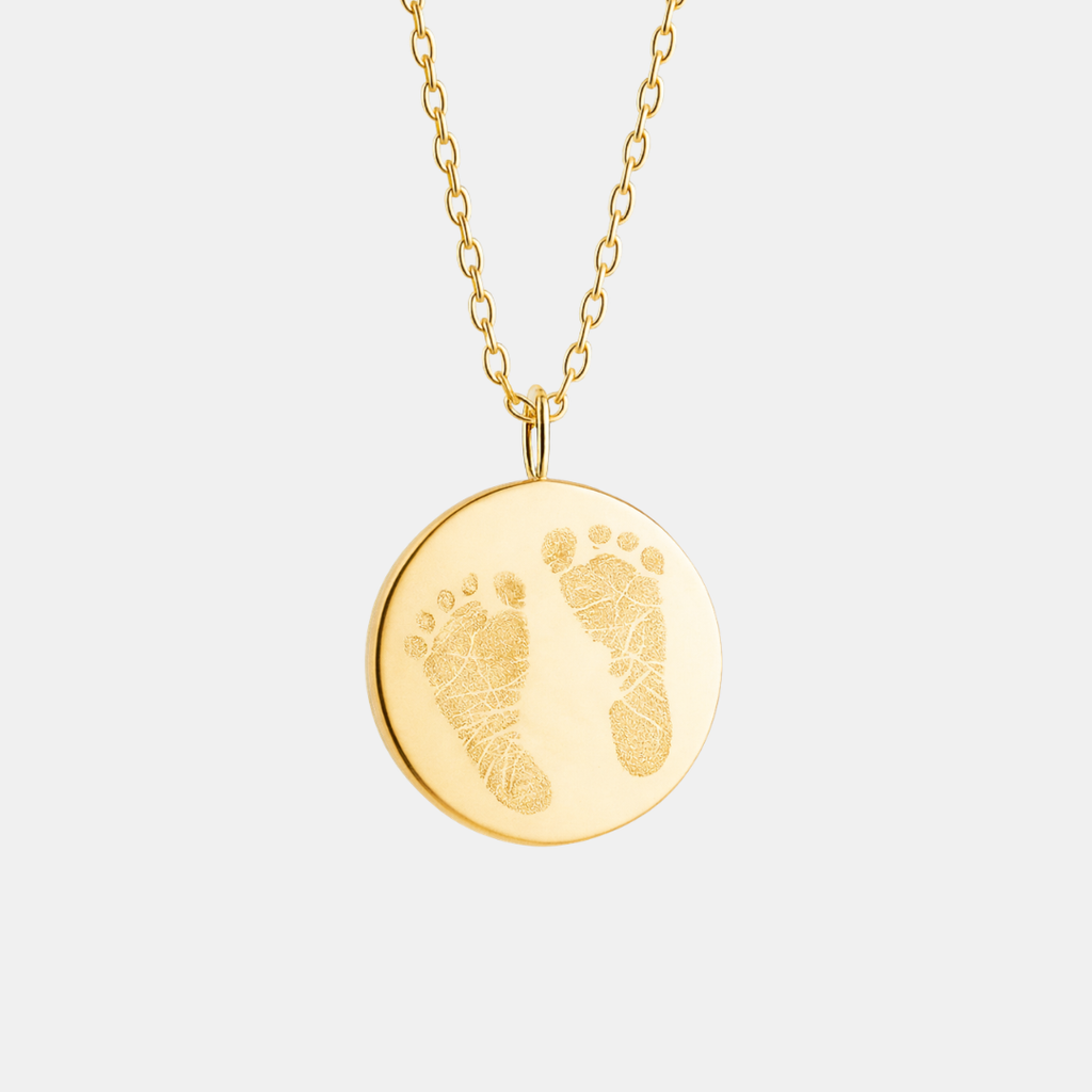 Front-facing product shot of custom engraved 18k gold vermeil 16mm coin pendant necklace on diamond-cut cable chain, showcasing personalised double newborn baby footprints with detailed toe and sole texture faithfully precision diamond-head engraved on warm high-polish gold disc – Atelier By Dsgn luxury custom footprint coin necklace meaningful gift for new mum, mothers day, baby shower, birth announcement or cherished newborn family heirloom necklace