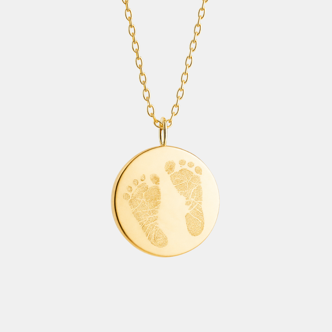 Front-facing product shot of custom engraved 18k gold vermeil 16mm coin pendant necklace on diamond-cut cable chain, showcasing personalised double newborn baby footprints with detailed toe and sole texture faithfully precision diamond-head engraved on warm high-polish gold disc – Atelier By Dsgn luxury custom footprint coin necklace meaningful gift for new mum, mothers day, baby shower, birth announcement or cherished newborn family heirloom necklace