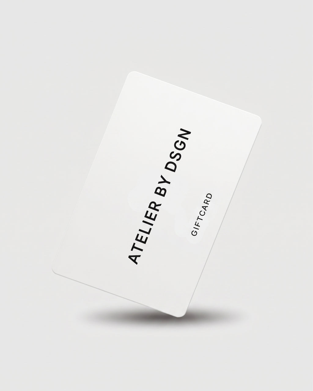 A white gift card with black text reading 'ATELIER BY DSGN' and 'GIFT CARD' on a light gray background with a soft shadow underneath.