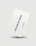 A white gift card with black text reading 'ATELIER BY DSGN' and 'GIFT CARD' on a light gray background with a soft shadow underneath.