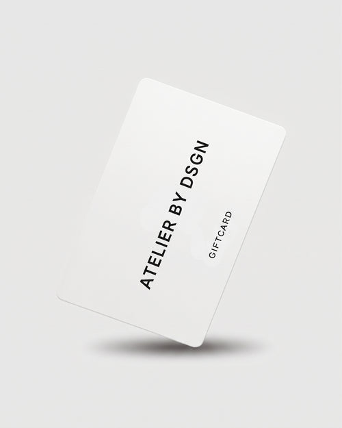 A white gift card with black text reading 'ATELIER BY DSGN' and 'GIFT CARD' on a light gray background with a soft shadow underneath.