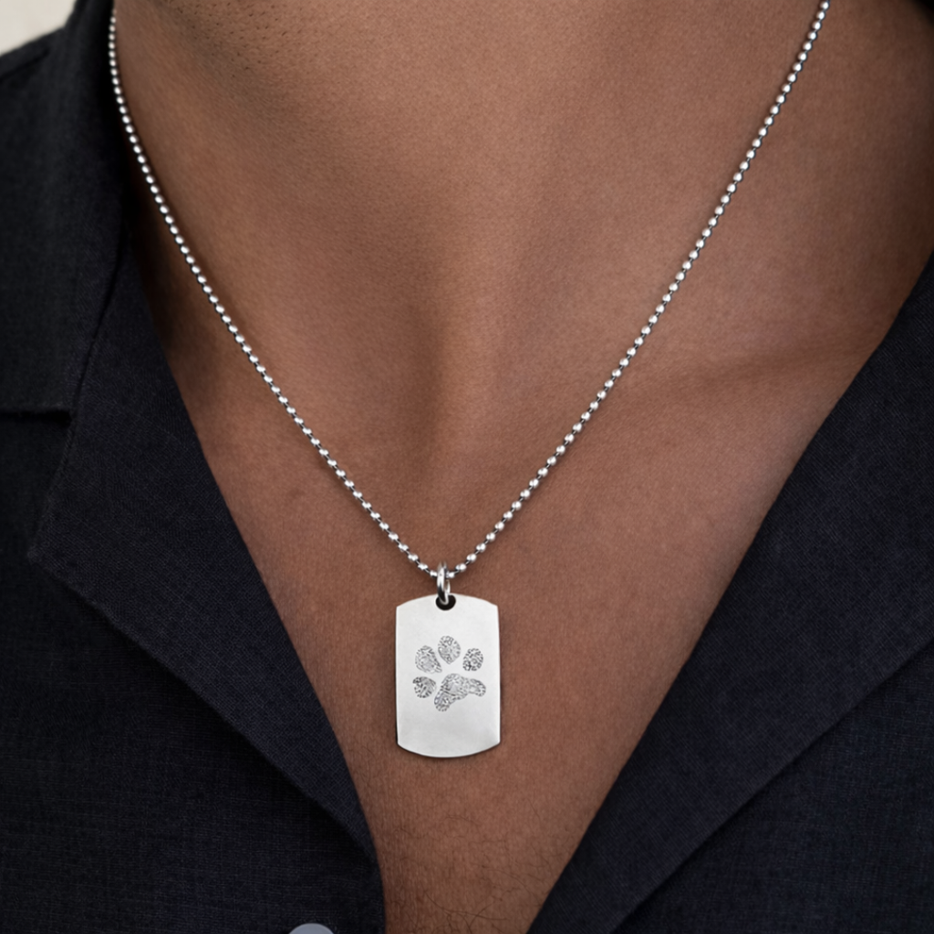 Custom engraved 925 sterling silver unisex paw print dog tag necklace worn on male model in dark blazer, personalised pet paw print with intricate texture detail precision diamond-head engraved on polished silver tag on 61cm bead chain – Atelier By Dsgn custom paw print jewellery everyday wear gift for dog lovers, cat lovers, pet mum, pet dad, pet memorial or rainbow bridge remembrance keepsake necklace