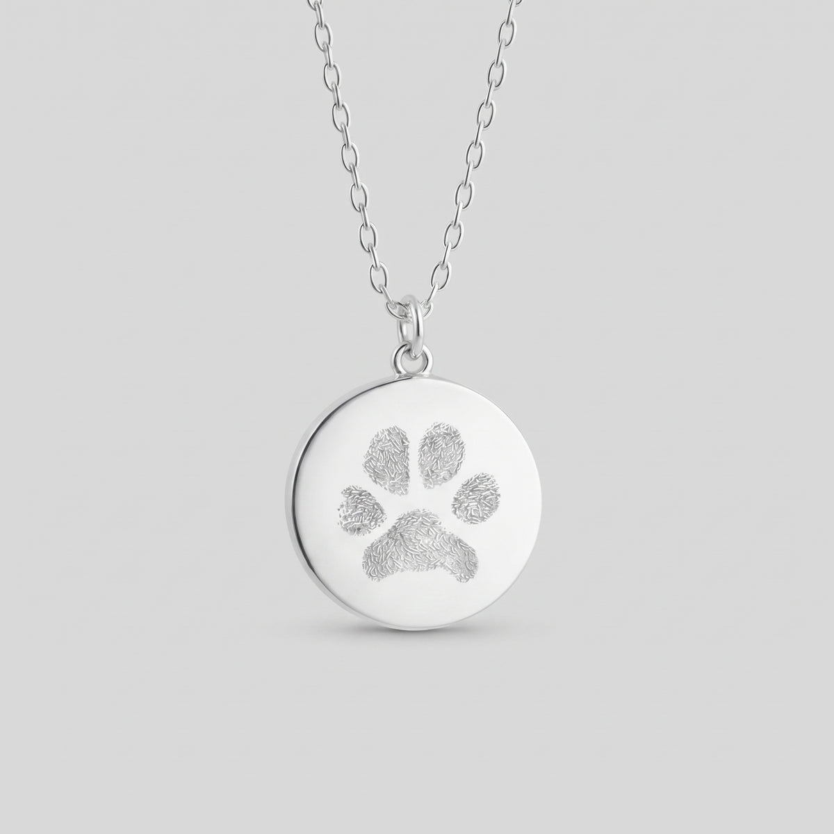 Custom engraved 925 sterling silver 16mm coin pendant necklace on diamond-cut cable chain, featuring a personalised pet paw print with intricate toe and pad texture detail precision diamond-head engraved on polished round disc.  Atelier By Dsgn custom paw print pendant jewellery meaningful gift for dog lovers, cat lovers, pet mum, pet dad, pet memorial, rainbow bridge remembrance or new pet adoption keepsake necklace.