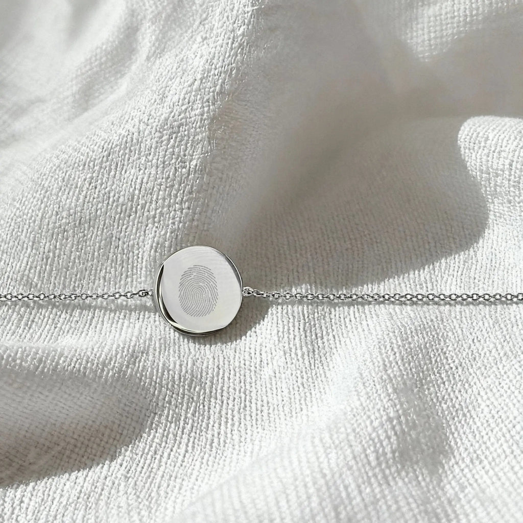 Single fingerprint coin bracelet in 925 sterling silver by Atelier By DSGN, displayed in a flatlay arrangement.