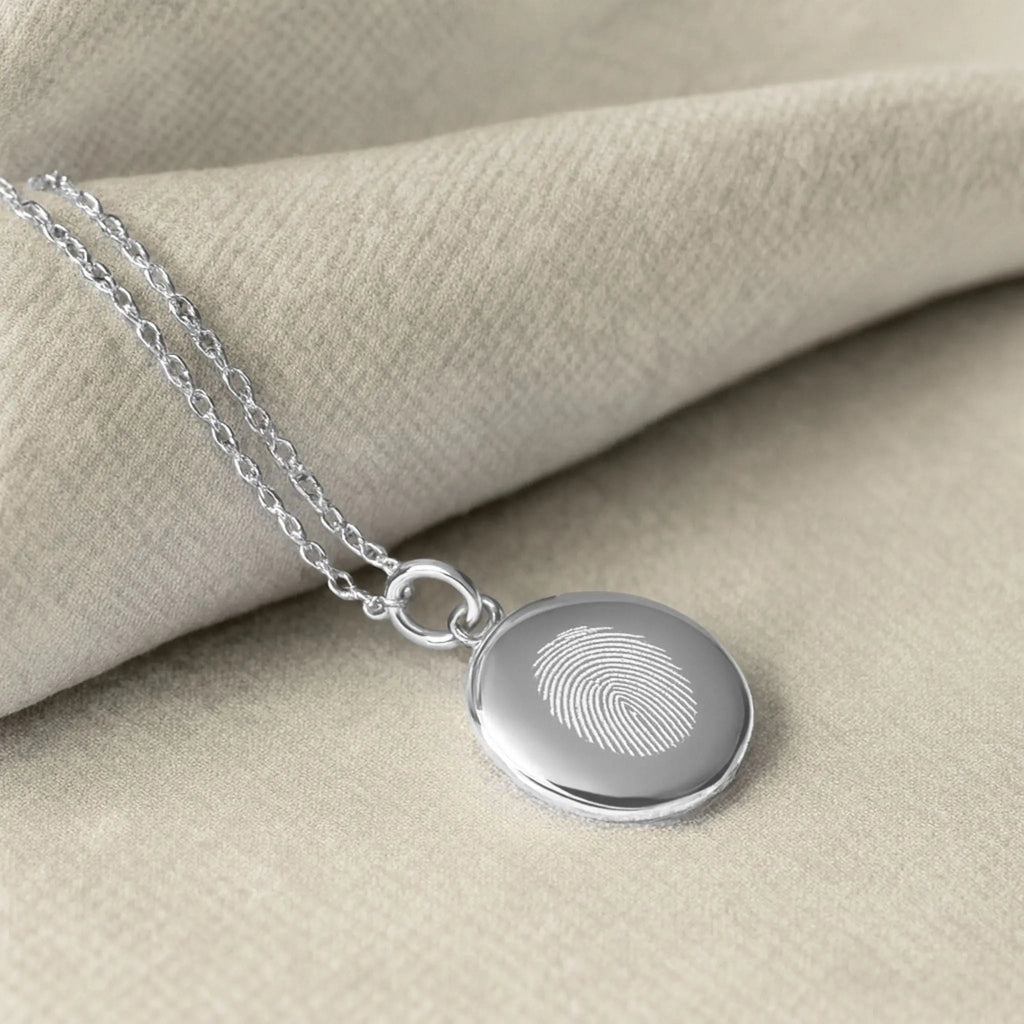 Elegant close-up of the Atelier By DSGN Single Fingerprint Necklace in 925 Sterling Silver, displayed on soft neutral fabric, featuring a diamond-engraved fingerprint pendant that captures love and individuality in timeless luxury craftsmanship.