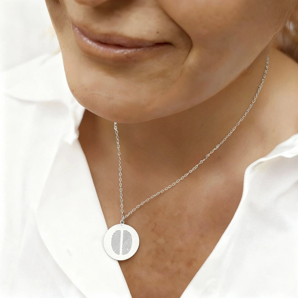 Close-up lifestyle image of the Atelier Two Fingerprint Pendant Necklace in 925 Sterling Silver, worn with a white blouse — a polished, elegant keepsake capturing two fingerprints as a symbol of love and connection.