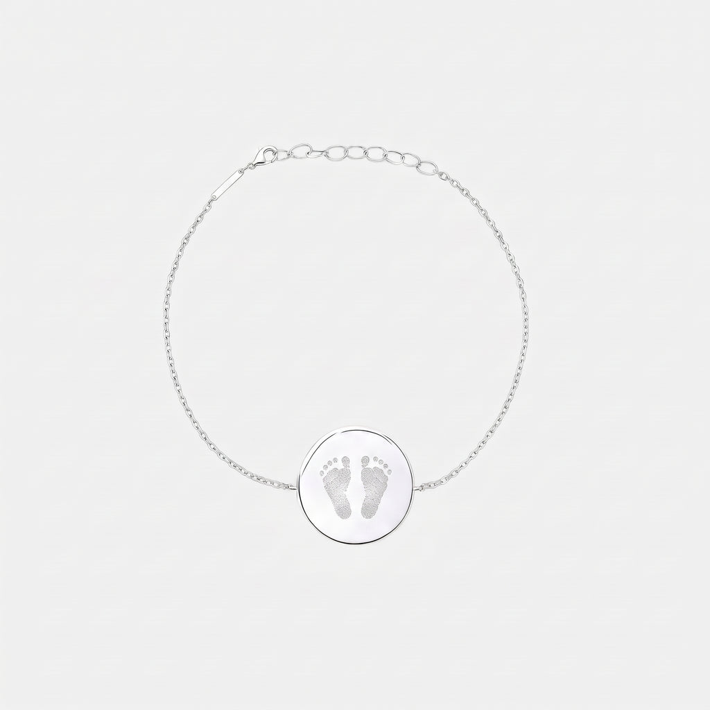 Custom engraved 925 sterling silver adjustable coin bracelet, featuring a personalised two newborn baby footprints with intricate toe and sole detail precision diamond-head engraved on polished round disc on delicate diamond-cut cable chain.  Atelier By Dsgn custom footprint coin bracelet meaningful gift for new mum, mothers day, baby shower, new baby arrival or treasured newborn family keepsake bracelet