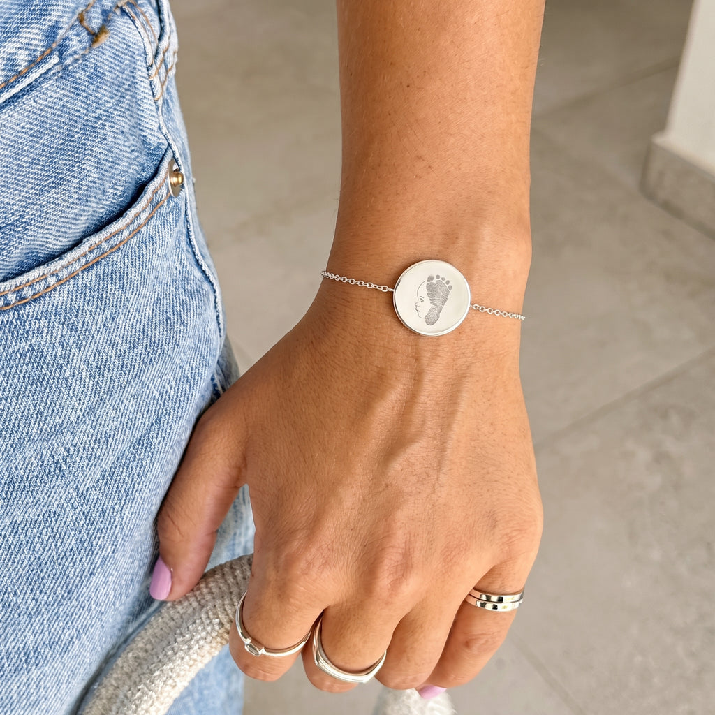 Custom Atelier By Design line art portrait and footprint engraved onto a 925 sterling silver coin pendant bracelet.  Meaningful jewelry from Atelier By DSGN.