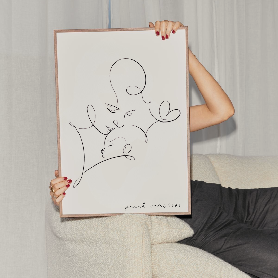 Woman holding framed custom single line drawing art of mother and baby with personalised name and date, minimalist portrait print gift idea