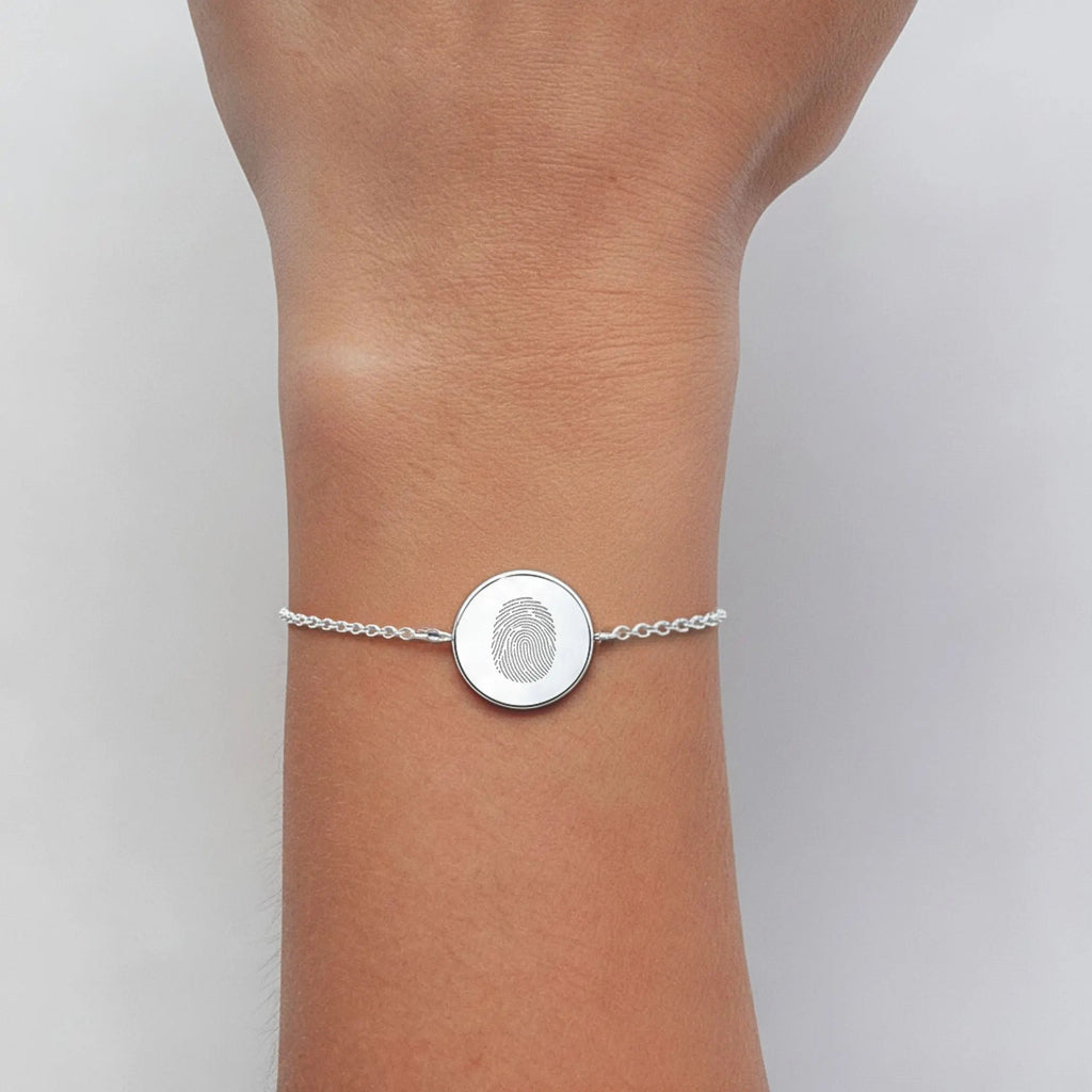 Single fingerprint coin bracelet in 925 sterling silver worn on a wrist, showcasing intricate design by Atelier By DSGN