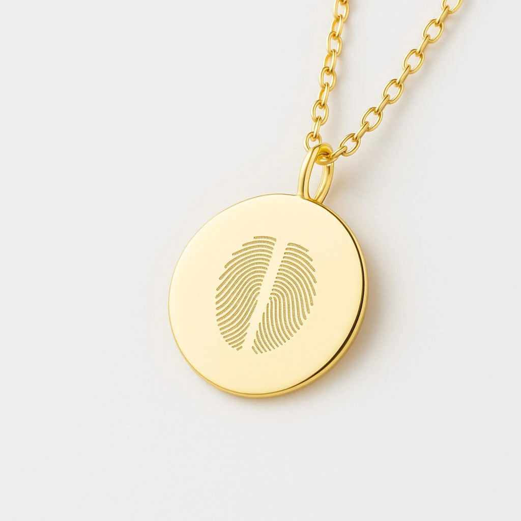 Two fingerprint pendant necklace in 18K gold vermeil by Atelier By DSGN,, featuring dual engraved fingerprints on a polished gold disc. A meaningful custom keepsake symbolizing connection, love, or family—crafted with precision for timeless, luxury personalization.