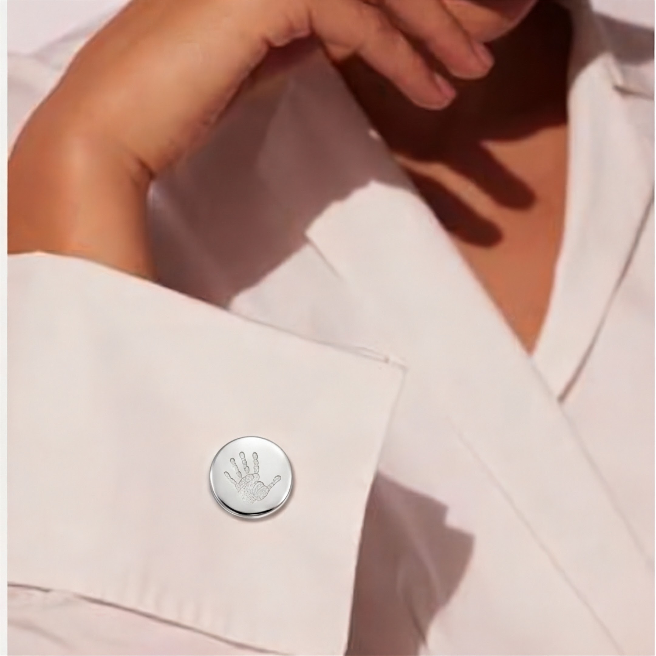 A custom engraved hand print, 925 sterling silver round cufflinks featuring personalised baby handprint with intricate finger and palm detail precision diamond-head engraved on polished silver face – Atelier By Dsgn custom handprint cufflinks on a model wearing a white dress shirt.