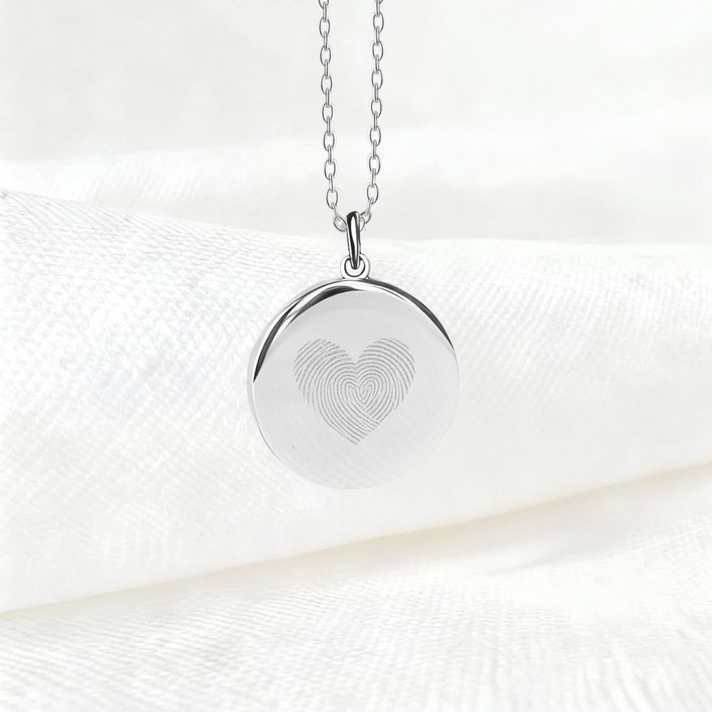 Heart Fingerprint Pendant Necklace in 925 Sterling Silver displayed on soft white fabric, featuring two fingerprints elegantly engraved to form a heart - a minimalist and meaningful symbol of love and connection.
