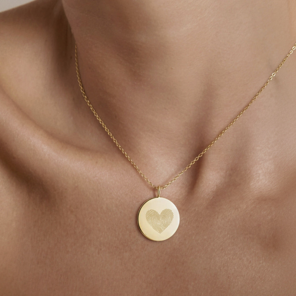 The Luxury Heart Fingerprint Necklace in 18K Gold Vermeil by Atelier shown worn on the neck. Featuring two fingerprints forming a heart shape, this personalised pendant captures love and connection in a minimalist gold design, perfect for everyday elegance or as a meaningful keepsake gift.