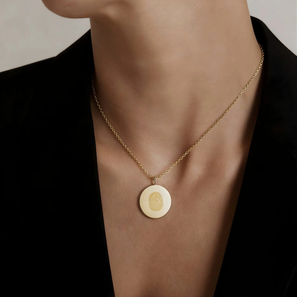 Model wearing a single fingerprint coin necklace in 18k gold vermeil by Atelier By DSGN , showcasing its elegant design.