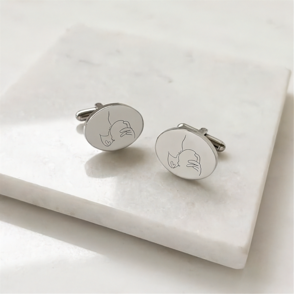 custom line art portrait engraved  coin cufflinks in sterling silver on a marble display table.  Engraving is of a lady holding her new born baby in beautiful line art.  Personalised cufflinks from Atelier By DSGN.