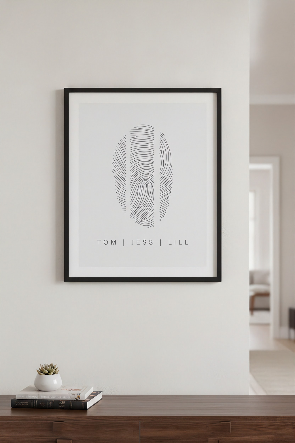 Three fingerprint family art in a black frame hanging above a console table, showcasing a personalized home décor and minimalist keepsake design.