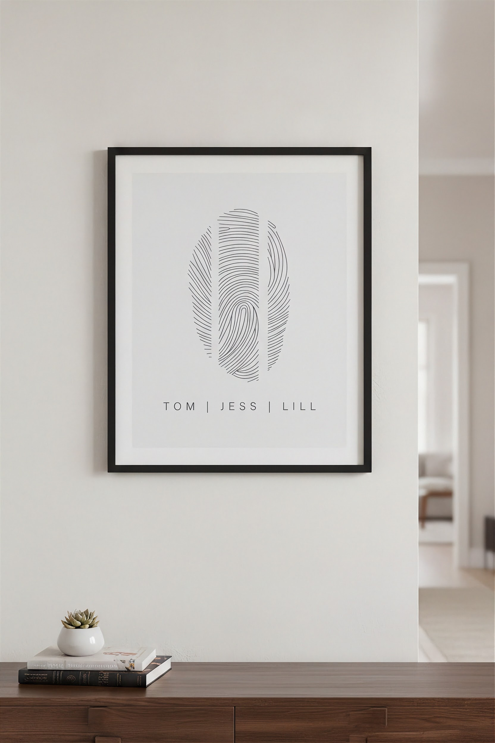 Three fingerprint family art in a black frame hanging above a console table, showcasing a personalized home décor and minimalist keepsake design.