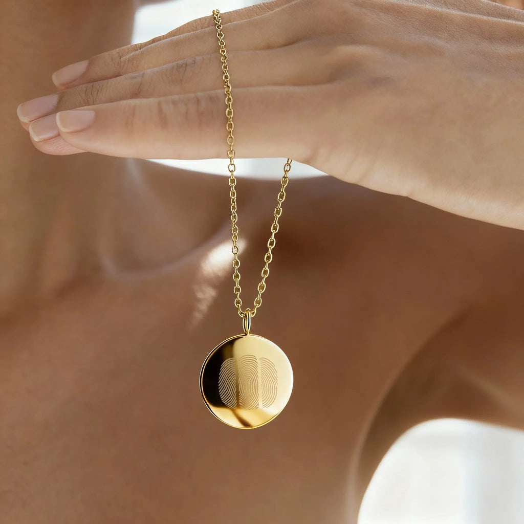 Close-up of the Luxury Three Fingerprint Coin Necklace in 18K Gold Vermeil by Atelier By DSGN. The pendant’s mirror-polished finish and precision-engraved fingerprints capture a minimalist yet meaningful design, celebrating love, connection, and craftsmanship in fine gold jewelry.