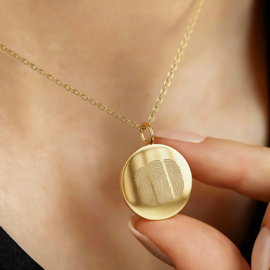 The Luxury Three Fingerprint Coin Necklace in 18K Gold Vermeil by Atelier By DSGN, shown worn close to the heart. The pendant features three finely engraved fingerprints symbolising love and connection, crafted from radiant gold vermeil for a timeless, heirloom-quality finish.