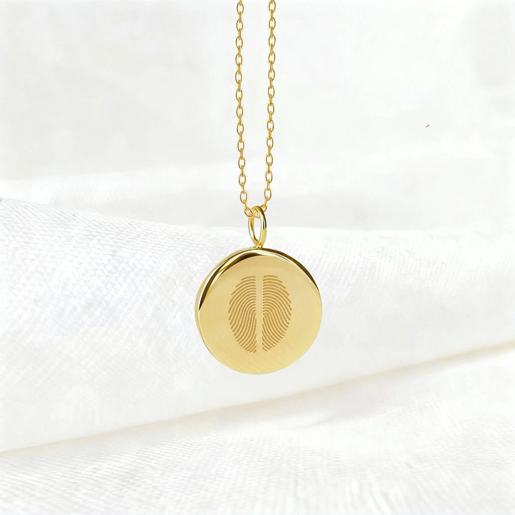 Two fingerprint pendant necklace in 18K gold vermeil by Atelier By DSGN, suspended elegantly against a soft white background. Features dual engraved fingerprints on a polished disc — a timeless, luxury keepsake symbolizing connection, unity, and bespoke craftsmanship.