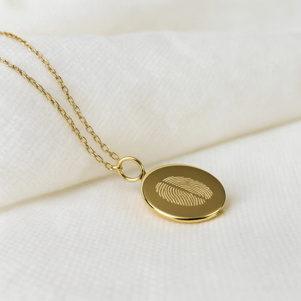 Close-up of the Two Fingerprint Pendant in 18K gold vermeil by Atelier By DSGN. Features finely engraved dual fingerprints on a smooth round disc with a delicate gold chain — a personalized luxury necklace representing love, connection, and individuality.